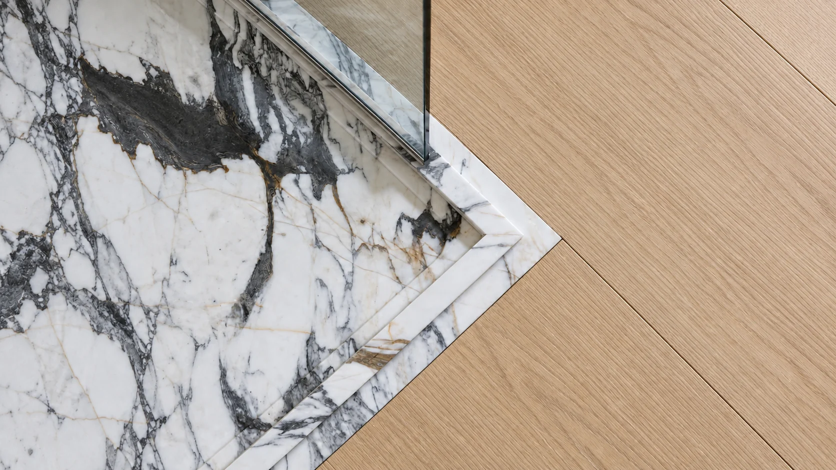 Illustrative image: veined marble meeting pale oak flooring at a precisely detailed glazed threshold.