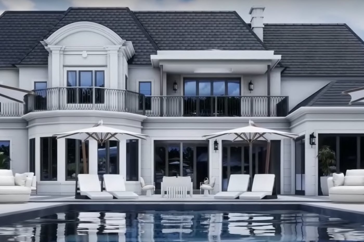 White residence and pool terrace with a dark roof and black-framed doors