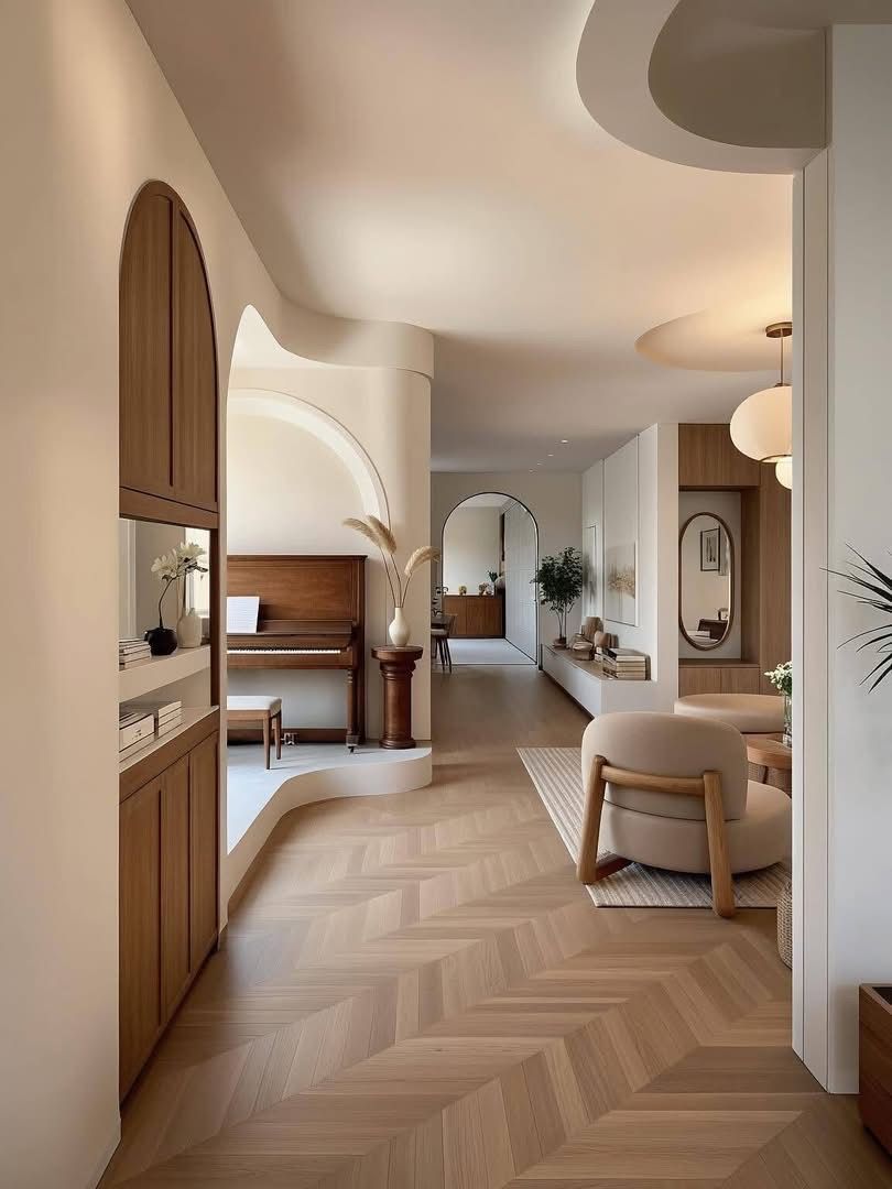 Pale interior with curved ceiling and wall openings, wood cabinetry, a piano and patterned wood-toned flooring