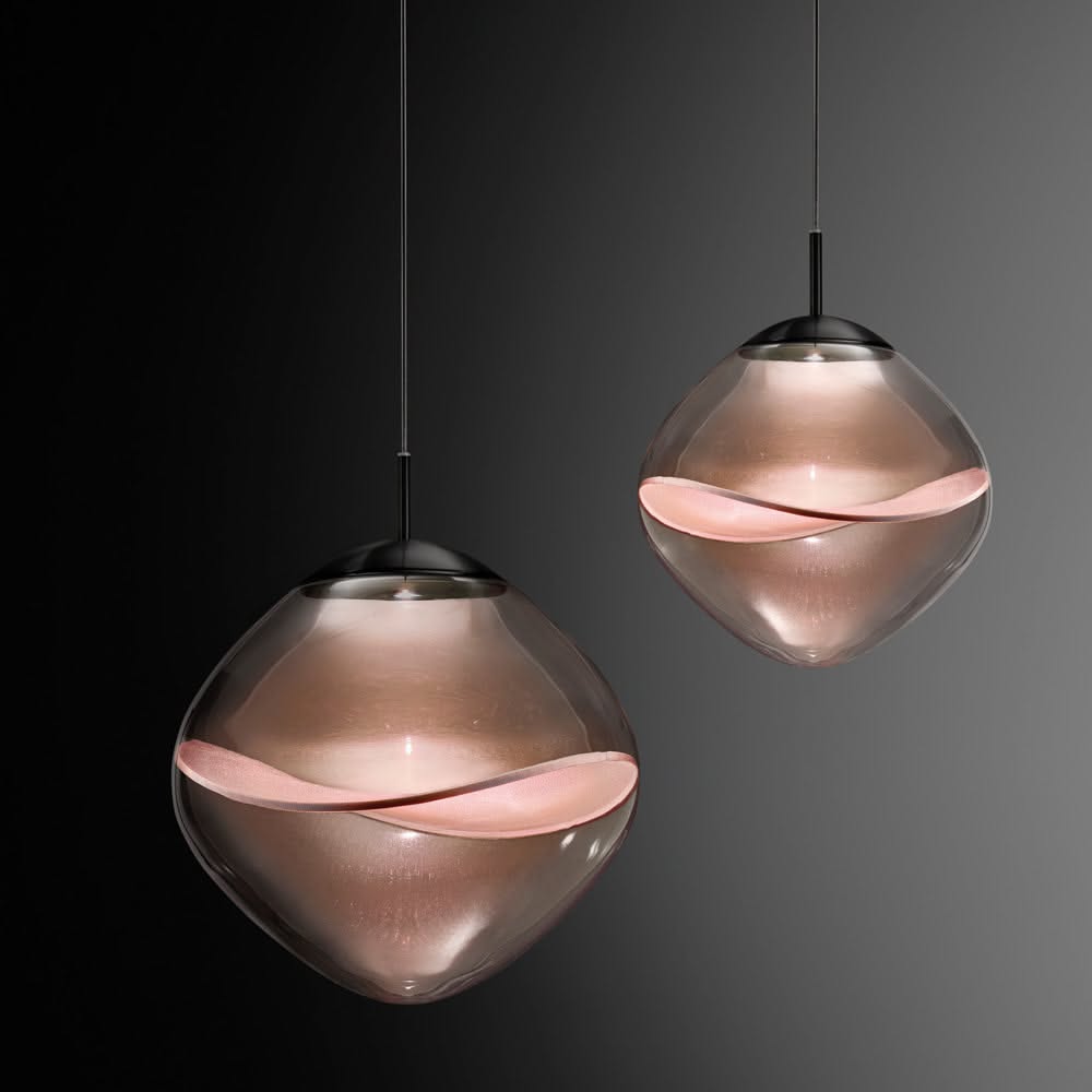 Two suspended rounded glass pendants glowing pale pink against a background that shifts from black to gray