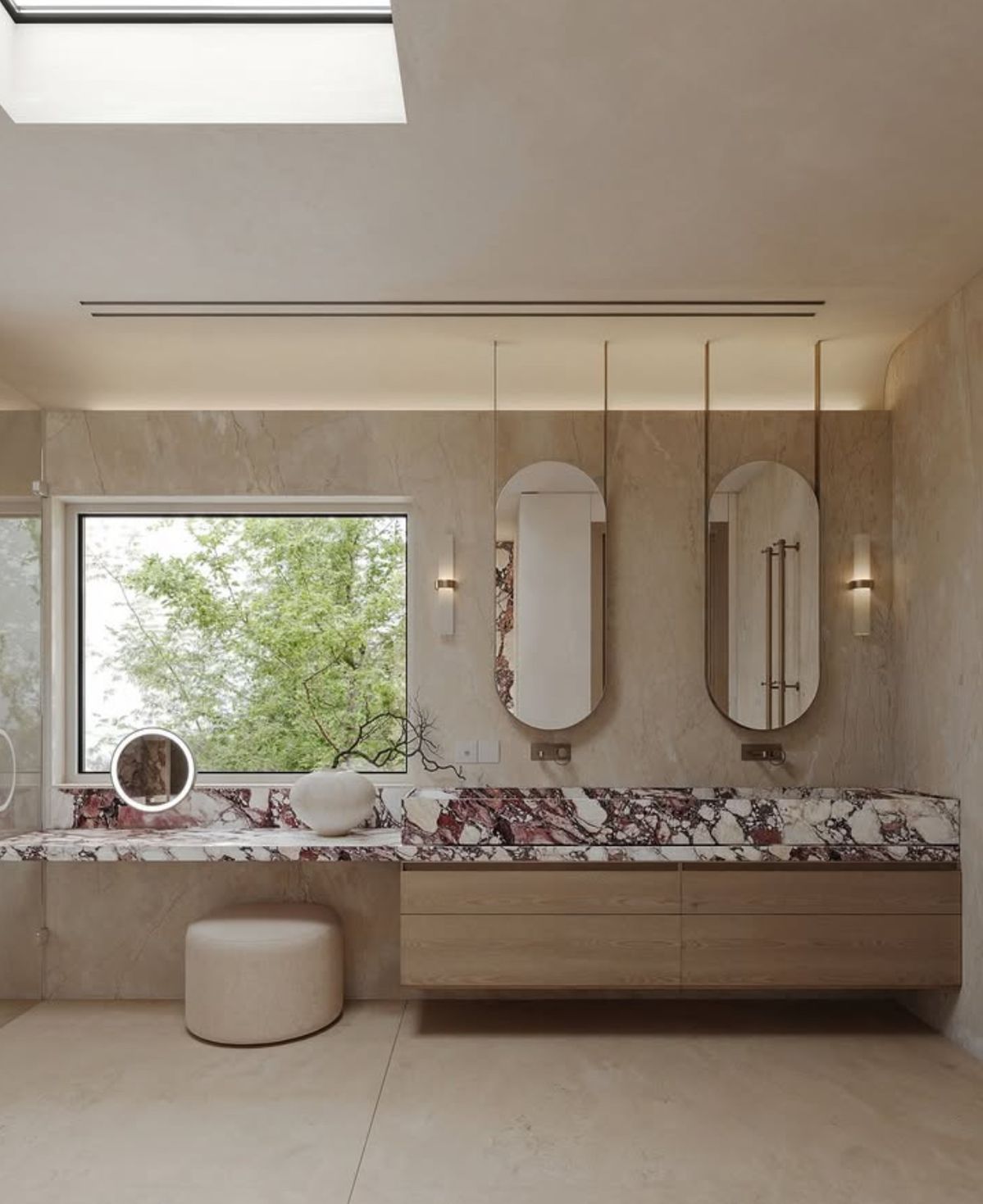 Burgundy-and-white veined vanity and low backsplash beneath oval mirrors and a window, with wood drawers below