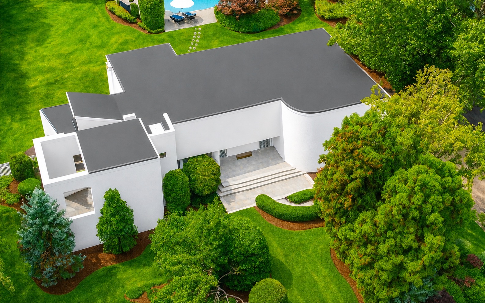 Aerial view of a white contemporary residence surrounded by mature landscaping