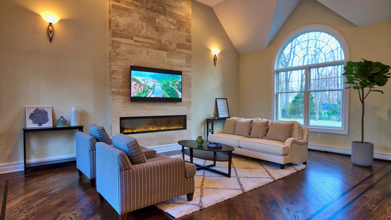 Living room in Saddle River after styling by B&Co. — arched window, stone fireplace and wood floor