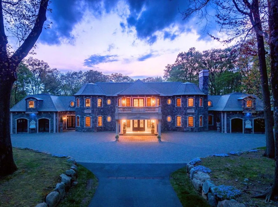 A stone estate at twilight from the B&Co. Realty magazine